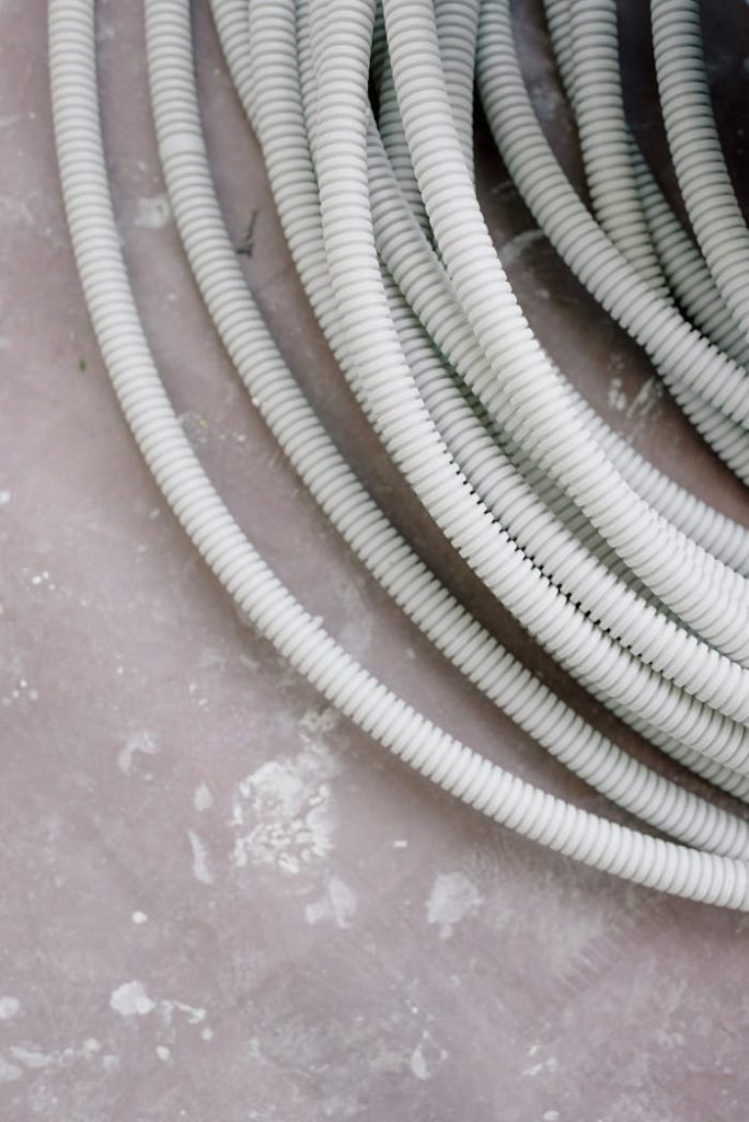 Close-up of coiled white electrical wire on a rough, textured concrete surface.